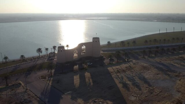 Aerial circling castle shaped building on Tarout Island coast at sunset