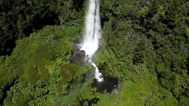 Drone shot of the waterfall at El Salto El Leon surrounded by vegetation and with a rainbow - crane shot