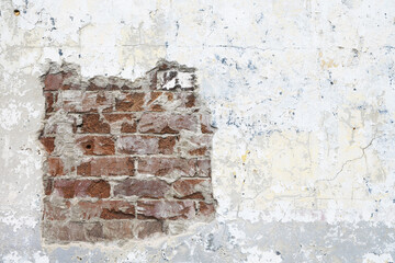 Worn plaster stucco wall with exposed brickwork