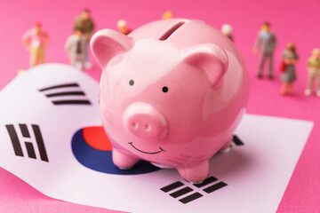 Piggy bank, flag of South Korea and plastic toy men on a colored background, the concept on the theme of income of the population of South Korea