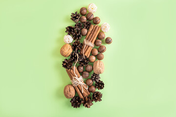Christmas or New Year natural composition of nuts, cones and cinnamon on the green background. Beige and green natural design.