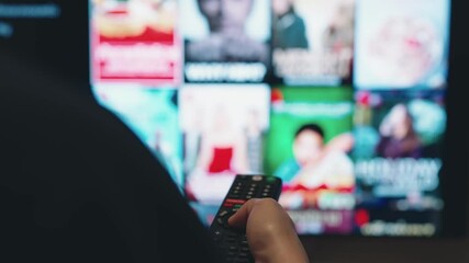 Online video streaming service, Hand holding remote control to select online movies on smart tv.