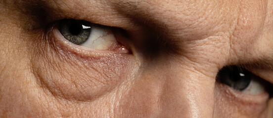 Close-up macro photo of the eyes of a middle-aged man. Intense look, wrinkles around the eyes.