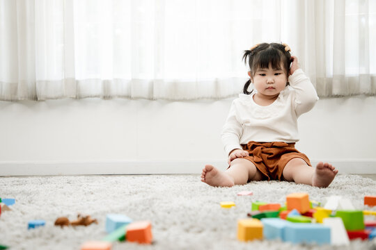 Cute Asian girl plays with wooden puzzles to enhance her age-appropriate systemic thinking skills and imagination. Concept of education and brain development of children.