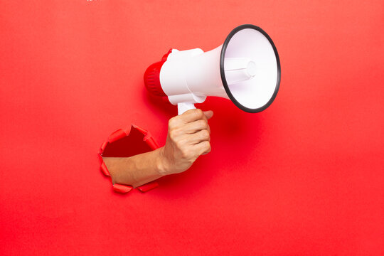 man hand holding a megaphone on red  background