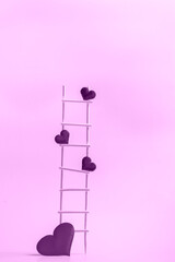 Wooden ladder with red hearts on a pink background. Postcard or invitation template. Closeup