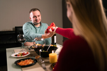 Two in love have dinner at home, a woman gives a man a surprise gift for an anniversary or valentine's day, wedding anniversary celebration, romantic