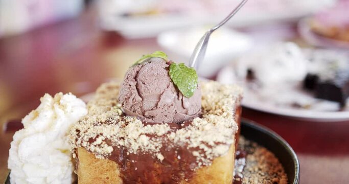 Scooping chocolate ice cream on top toast with spoon. Popular dessert toast topping with ice cream.