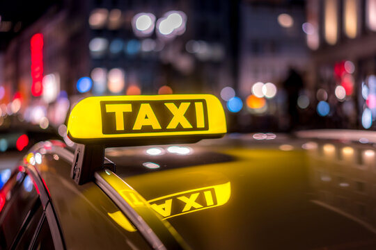 Gelbes beleuchtetes Taxischild in der Nacht