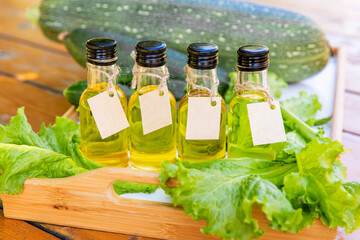 Four types of vegetable oil in small bottles with cardboard labels on the background of salad...
