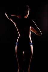 Portrait Swim wear of 20s Asian Woman in shadow low light key with back backlit, side rear view