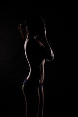 Portrait Swim wear of 20s Asian Woman in shadow low light key with back backlit, side rear view