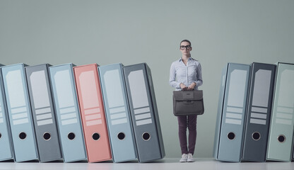 Confused businesswoman standing next to huge ring binders