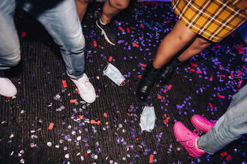 Friends stepping on confetti and face masks at a party