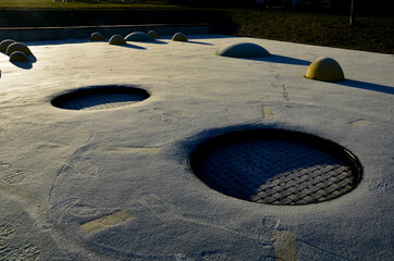 white rubber surface of a playground with yellow scoops and colored spots in the frost of human...