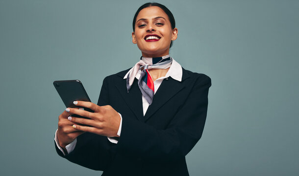 Happy air hostess using a smartphone in a studio