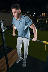 Fototapeta na wymiar Concentrated male athlete performing advanced strength-training exercise