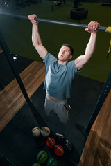 Strong young man doing dead hang exercise