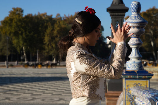 Flamenco dancer, woman, brunette and beautiful typical spanish dancer is dancing and clapping her hands in a square in seville. Flamenco concept of cultural heritage of humanity.