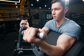 Tranquil sporty man working out on fitness machin