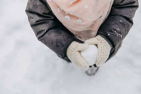 Closeup of a child in mittens making a snowball.