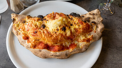 Pizza calzone closed on restaurant table white plate background