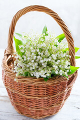 Fototapeta na wymiar Basket with lilies of the valley on the table, selective focus