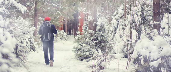 A man travels with a backpack. Winter hike in the forest. Tourist on a walk in the winter in the park.