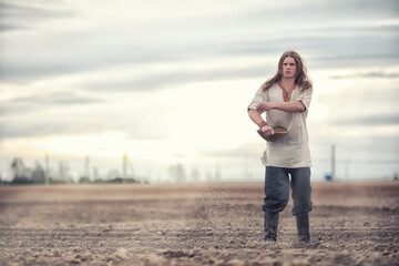 A young peasant sows the field with grain