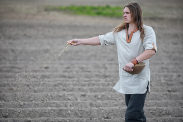 A young peasant sows the field with grain