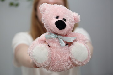 Cute pink teddy bear in girls hand close up