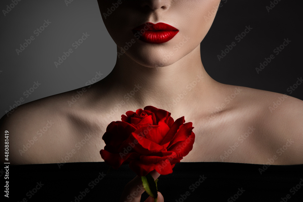 Wall mural Red Rose Flower and Model Lips Close up Fine Art Portrait. Beauty Model Face and Shoulders Make up. Elegant Mysterious Lady over Black