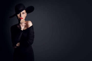 Fashion Woman Model in Hat showing Shh Sign of Silent Gesture putting finger in Red Lips. Elegant...