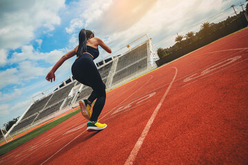 Fit young woman running sprinting at the racetrack. Fit runner fitness runner during outdoor...