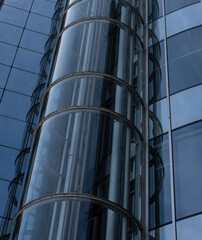 a transparent round elevator at a glass facade