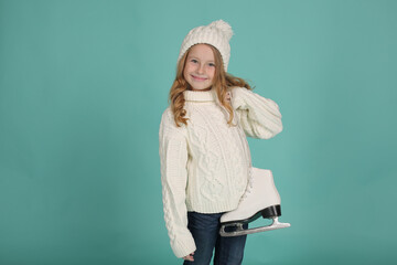 a girl in a white knitted sweater and a white hat holds white figure skating skates in her hands