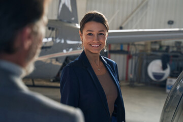 Joyful lady standing before man in aircraft hangar