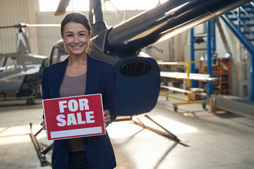 Cheerful aircraft hangar manager selling private helicopter