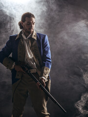 American revolution war soldier with flag of colonies and musket gun over dramatic smoke background. 4 July independence day of USA concept photo composition: soldier and flag. - 480883890