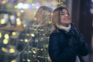 girl christmas lights evening decorated city, a young model on the background of urban decorations and garlands, night city lights