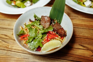 noodles with veal and vegetables on a gray table
