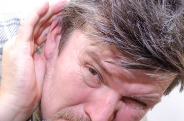 The man is eavesdropping. A male with ruffled hair.