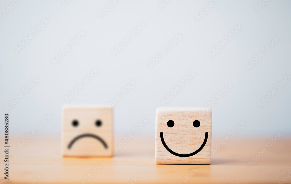 Poster focus of smile face and defocus of sad face on wooden block cube for positive mindset selection conc