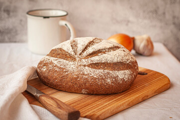 a loaf of bread on the on a wooden background with garlic and white cup