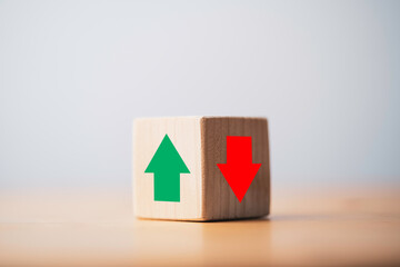 Focus of green up arrow in bright side and red down arrow in dark side which print screen on wooden cube block for economic and business profit growth concept.