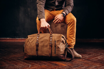Hand of man holding a brown canvas travel bag