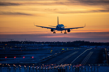 Airplane landing to airport runway in sunset - obrazy, fototapety, plakaty