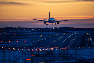 Airplane landing to airport runway in sunset