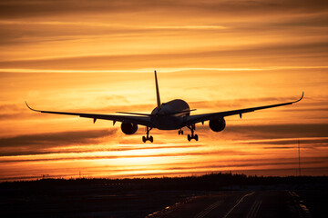 Airplane landing to airport runway in sunset