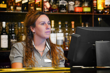Woman bartender in hotel bar. Female bartender at the cash register